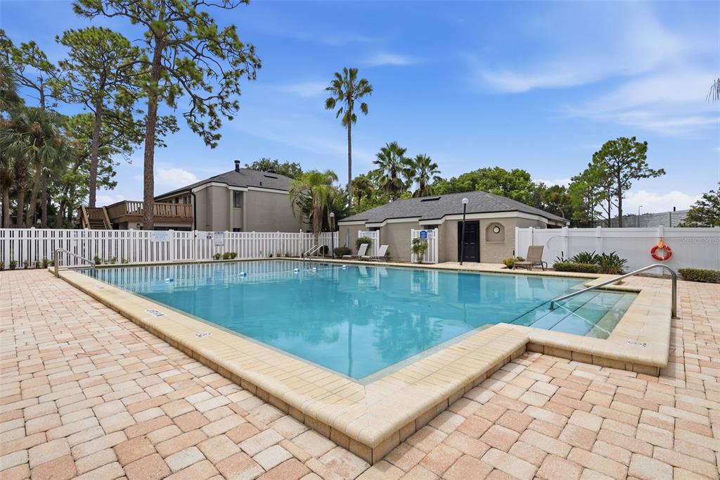 A rectangular swimming pool with a paver deck, white vinyl fencing, and a small clubhouse — 171 SPRINGWOOD CIRCLE UNIT C, LONGWOOD, FL