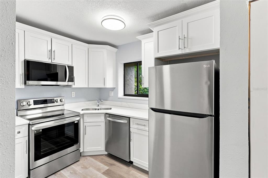 A kitchen with white cabinets, stainless steel appliances, and light-colored flooring — 171 SPRINGWOOD CIRCLE UNIT C, LONGWOOD, FL