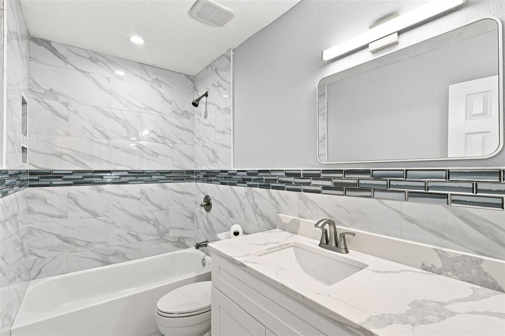 A screened-in balcony with wooden flooring overlooks a grassy area and neighboring apartment buildings — 171 SPRINGWOOD CIRCLE UNIT C, LONGWOOD, FL