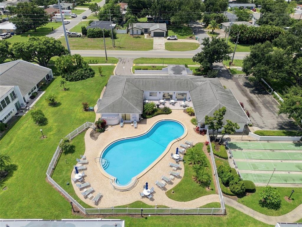 An aerial view shows a community clubhouse with a swimming pool and shuffleboard courts — 1655 S HIGHLAND AVENUE UNIT B110, CLEARWATER, FL