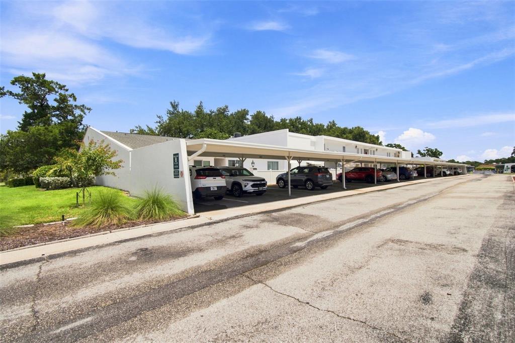 A white apartment building with a long covered parking area and several parked cars — 1655 S HIGHLAND AVENUE UNIT B110, CLEARWATER, FL