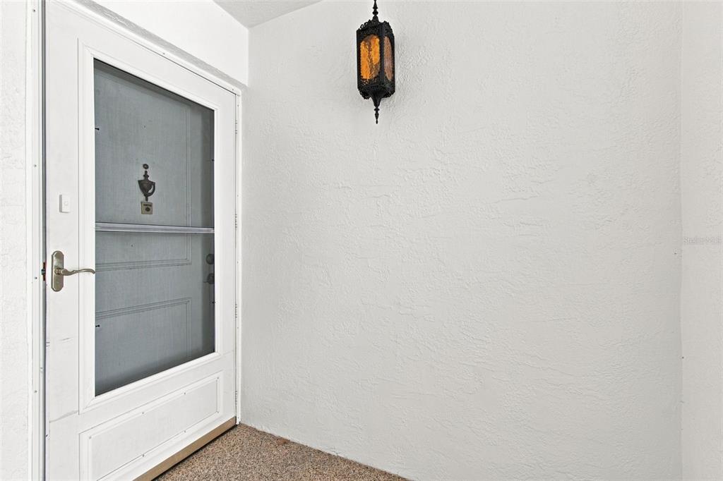 A white storm door with a decorative hanging lantern light on a textured wall — 1655 S HIGHLAND AVENUE UNIT B110, CLEARWATER, FL