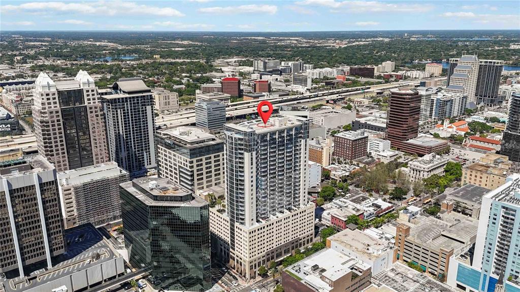 An aerial view of a high-rise building in a city with a red location pin — 155 S COURT AVENUE UNIT 1609, ORLANDO, FL