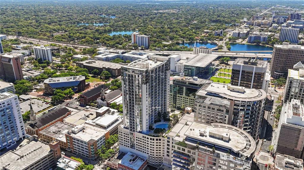 An aerial view of a city skyline featuring a tall residential tower with a pool — 155 S COURT AVENUE UNIT 1609, ORLANDO, FL