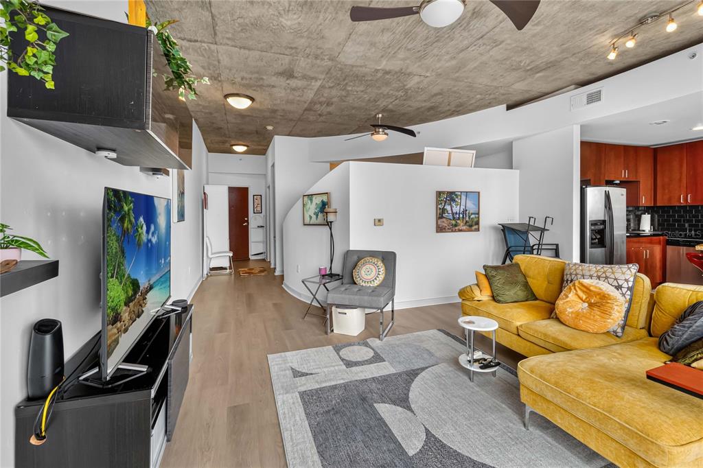 A living room features a yellow sectional sofa, a concrete ceiling, and light wood flooring — 155 S COURT AVENUE UNIT 1609, ORLANDO, FL