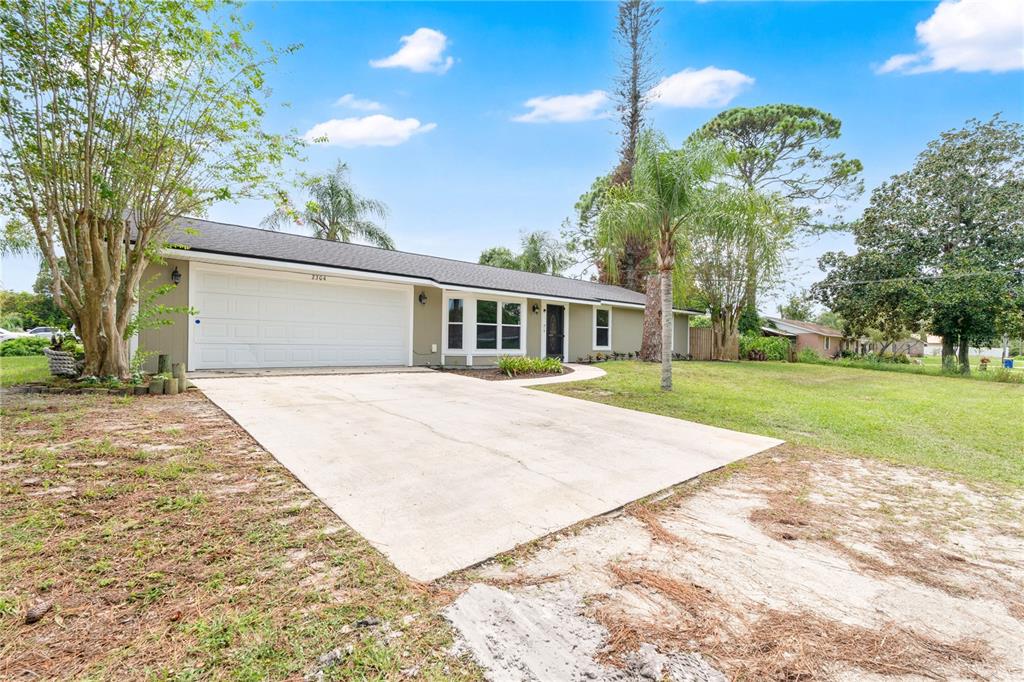 A single-story house with a white garage door, concrete driveway, and a grassy front yard — 2304 TRAVELERS PALM DRIVE, EDGEWATER, FL