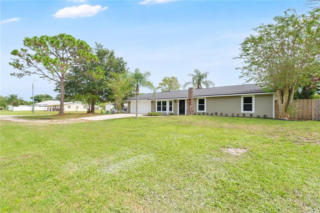 A single-story house with a light-colored exterior, a garage, and a large front lawn — 2304 TRAVELERS PALM DRIVE, EDGEWATER, FL
