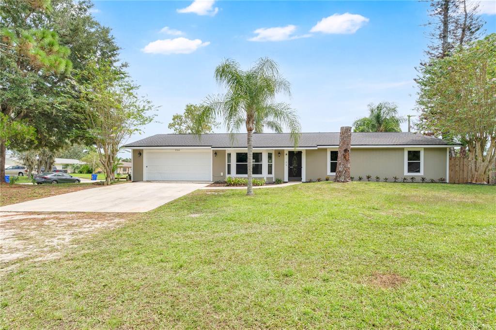 A single-story house with a two-car garage, a palm tree, and a large front lawn — 2304 TRAVELERS PALM DRIVE, EDGEWATER, FL