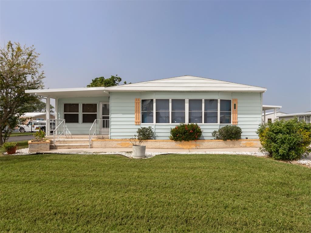 A light blue single-story manufactured home with a front porch and a grassy lawn — 628 LA JOLLA CIRCLE, NORTH PORT, FL
