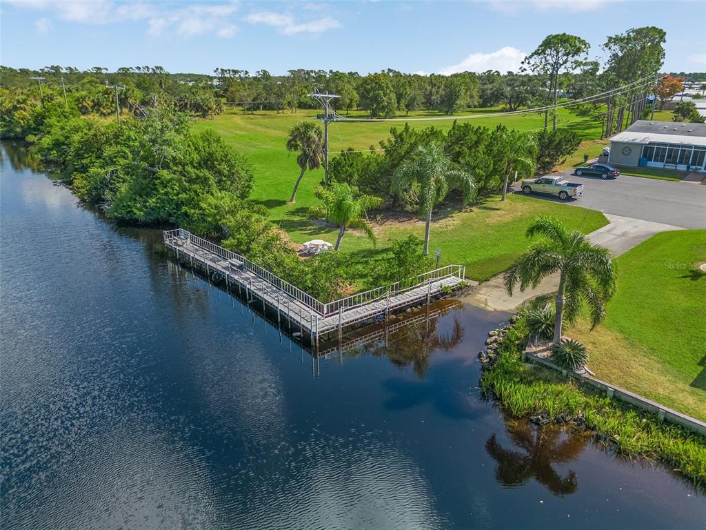 An aerial view shows a wooden dock extending into a canal beside a grassy yard — 628 LA JOLLA CIRCLE, NORTH PORT, FL