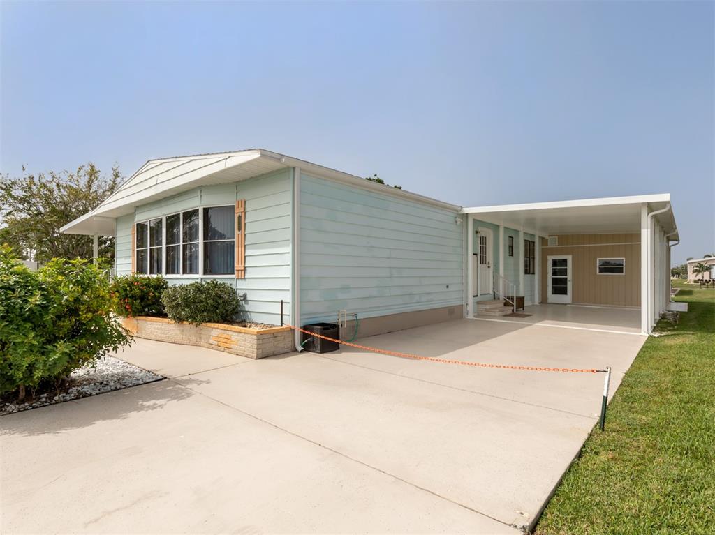 A light blue mobile home with a concrete driveway and an attached carport — 628 LA JOLLA CIRCLE, NORTH PORT, FL