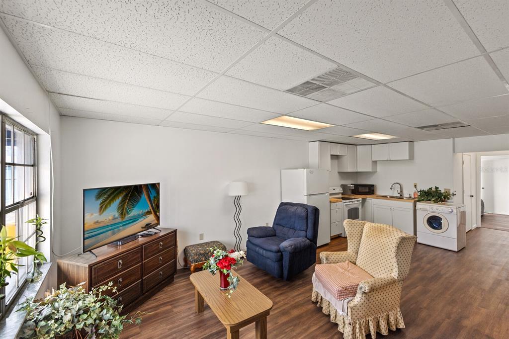 A living room with wood-look flooring, a kitchenette, and a drop ceiling with recessed lighting — 5550 15TH STREET E, BRADENTON, FL