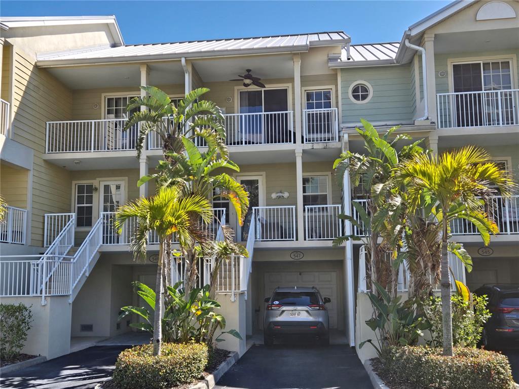 A three-story townhouse exterior features balconies, a ground-level garage, and palm trees — 547 BAHIA BEACH BOULEVARD, RUSKIN, FL