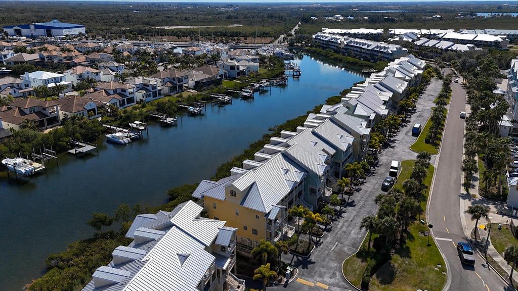 An aerial view shows a waterfront residential complex with townhomes, boat docks, and a road — 547 BAHIA BEACH BOULEVARD, RUSKIN, FL