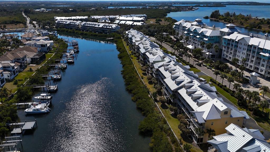 An aerial view shows a canal lined with multi-story residential buildings and private boat docks — 547 BAHIA BEACH BOULEVARD, RUSKIN, FL