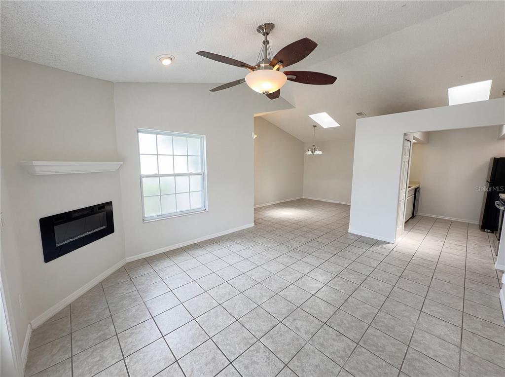 A living room with tile floors, a ceiling fan, a fireplace, and an adjacent kitchen — 2000 PLAINFIELD DRIVE, ORLANDO, FL