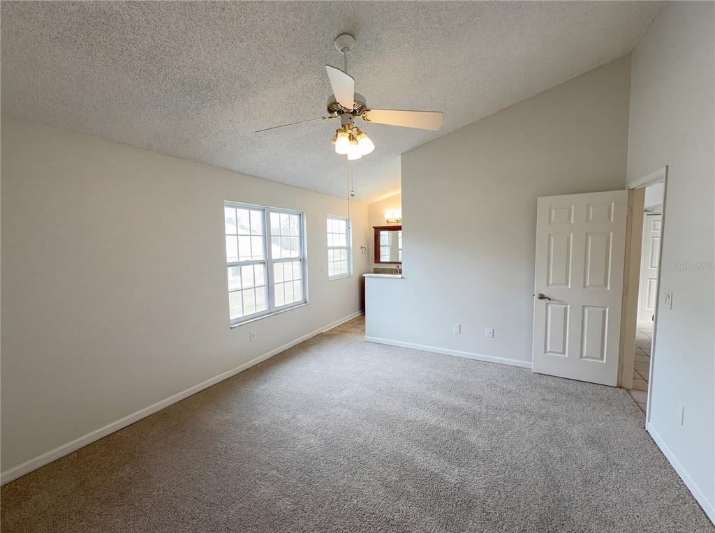 A carpeted bedroom features a vaulted ceiling, a ceiling fan, and an attached bathroom area — 2000 PLAINFIELD DRIVE, ORLANDO, FL