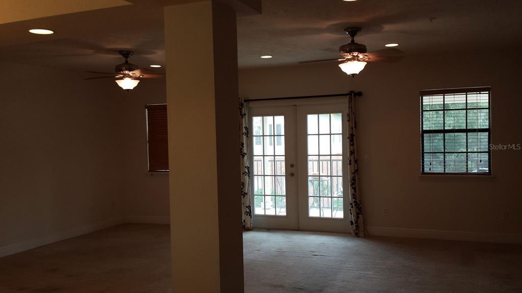 A carpeted room features a central pillar, two ceiling fans, French doors, and a window — 2602 SW 87TH DRIVE UNIT 201, GAINESVILLE, FL