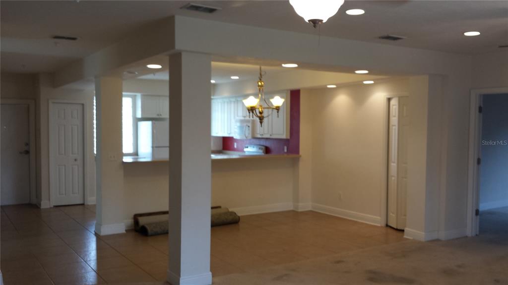 A kitchen with white cabinets and a breakfast bar overlooks an open living area — 2602 SW 87TH DRIVE UNIT 201, GAINESVILLE, FL