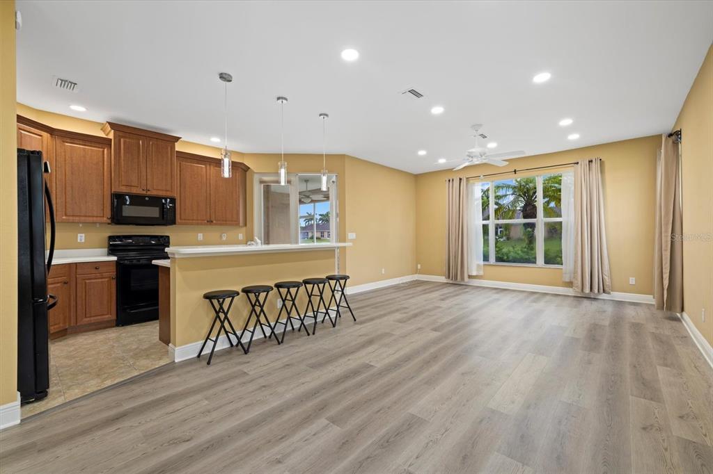 A kitchen with wood cabinets and a breakfast bar opens into a spacious living area — 4331 TURNBERRY CIRCLE, NORTH PORT, FL