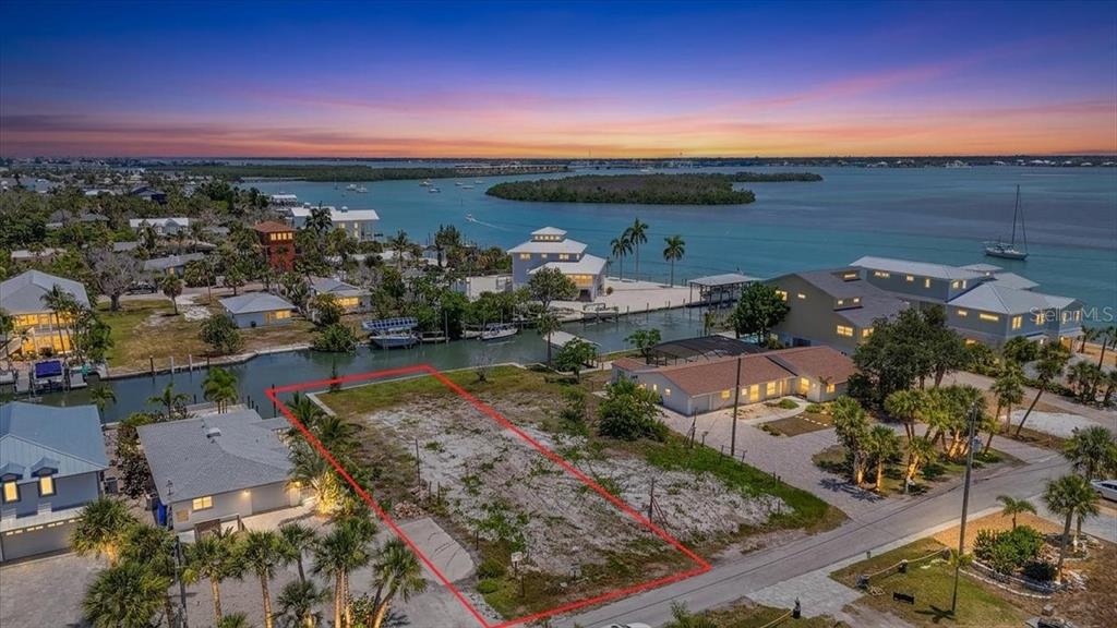 An aerial view shows a vacant waterfront lot outlined in red next to existing houses — 180 MOCKINGBIRD LANE, ENGLEWOOD, FL