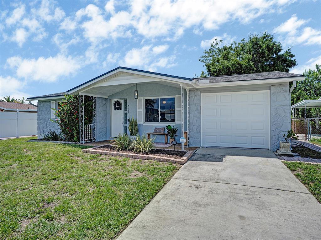 A single-story house with a light blue exterior, a front porch, and an attached garage — 2603 SOCIETY DRIVE, HOLIDAY, FL