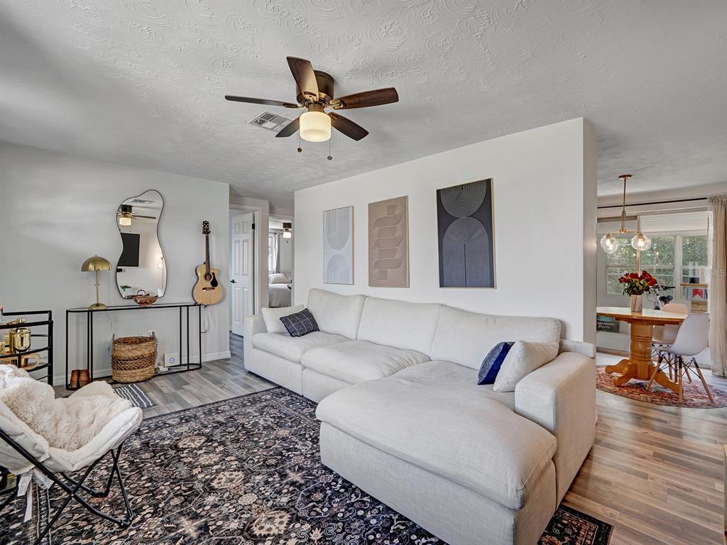 A living room features a white sectional sofa, a patterned rug, and a dining area — 2603 SOCIETY DRIVE, HOLIDAY, FL