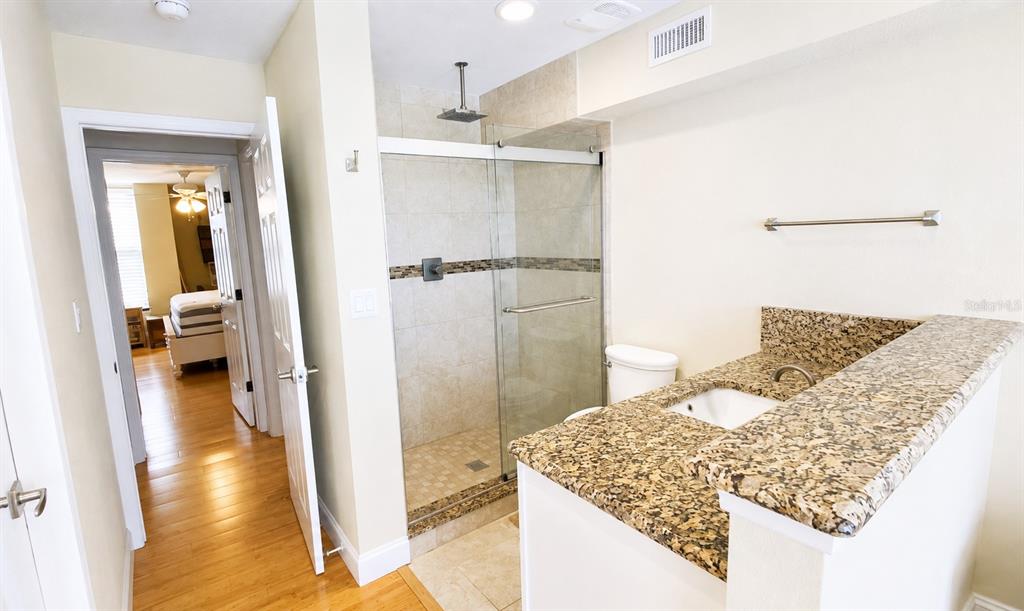 A bathroom features a granite-topped vanity, a glass-enclosed shower, and a doorway leading to a bedroom — 5500 OCEAN SHORE BOULEVARD UNIT UT23, ORMOND BEACH, FL