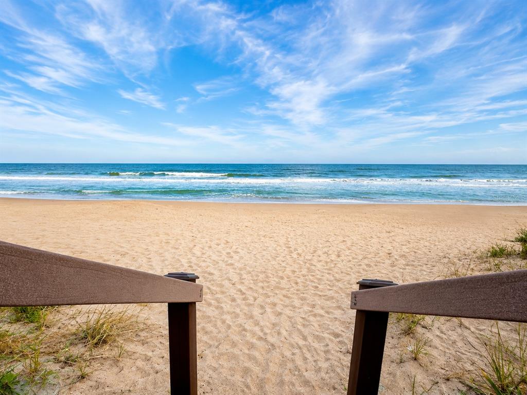 A view of a sandy beach and the ocean from a wooden staircase — 5500 OCEAN SHORE BOULEVARD UNIT UT23, ORMOND BEACH, FL