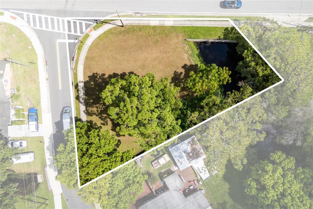An aerial view shows a vacant, triangular-shaped lot with trees and a small pond — SEMINOLA BOULEVARD, CASSELBERRY, FL