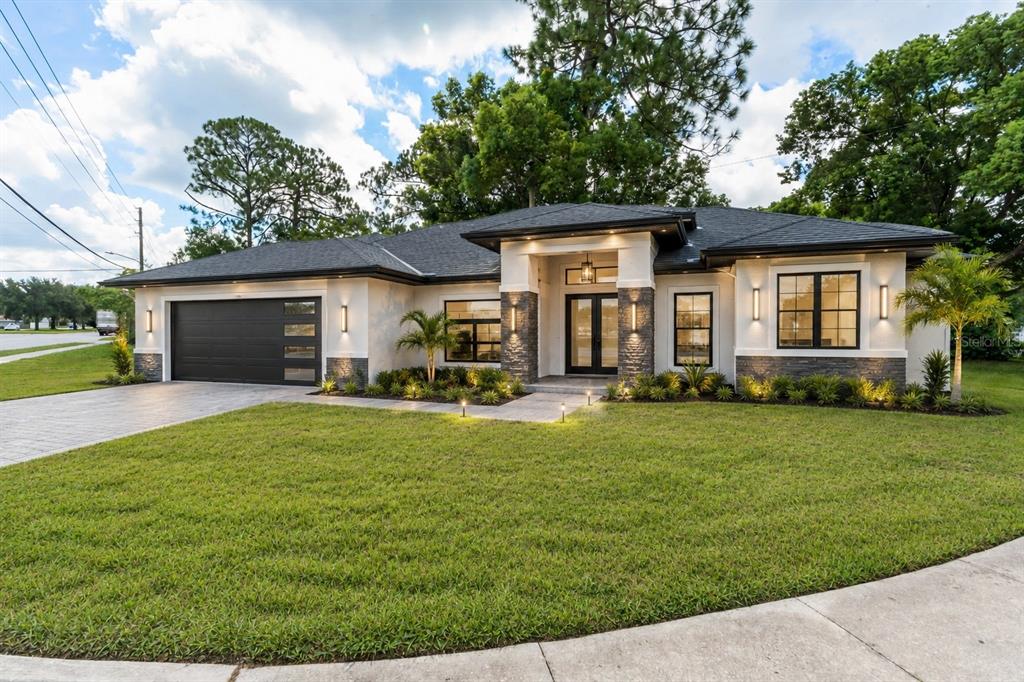 A modern single-story house with a dark garage, stone accents, and a landscaped front yard — SEMINOLA BOULEVARD, CASSELBERRY, FL
