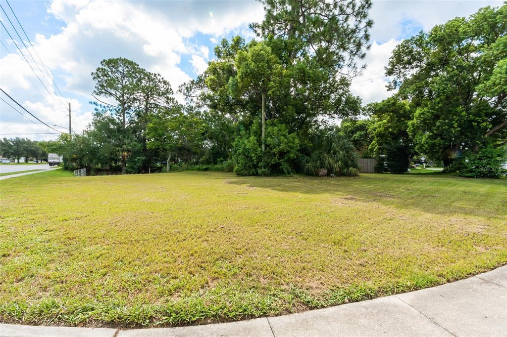 A vacant, grassy residential lot features mature trees and a sidewalk in the foreground — SEMINOLA BOULEVARD, CASSELBERRY, FL