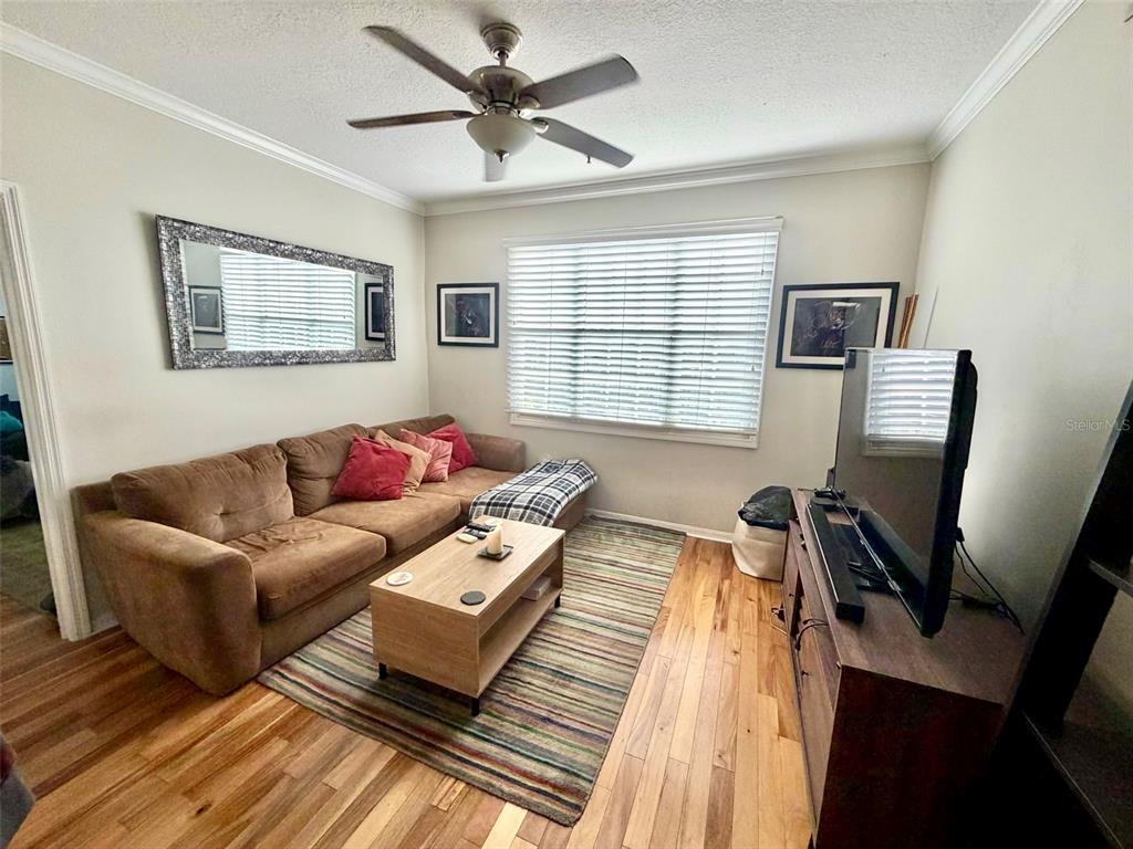 A living room features a brown sectional sofa, a wooden coffee table, and wood flooring — 501 KNIGHTS RUN AVENUE UNIT 2211, TAMPA, FL