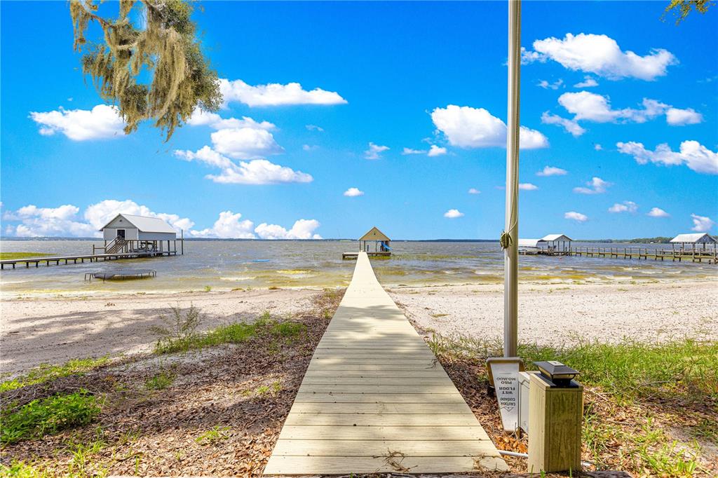 A wooden dock extends from a sandy beach toward a small boat house on water — 12360 E HIGHWAY 25, OCKLAWAHA, FL