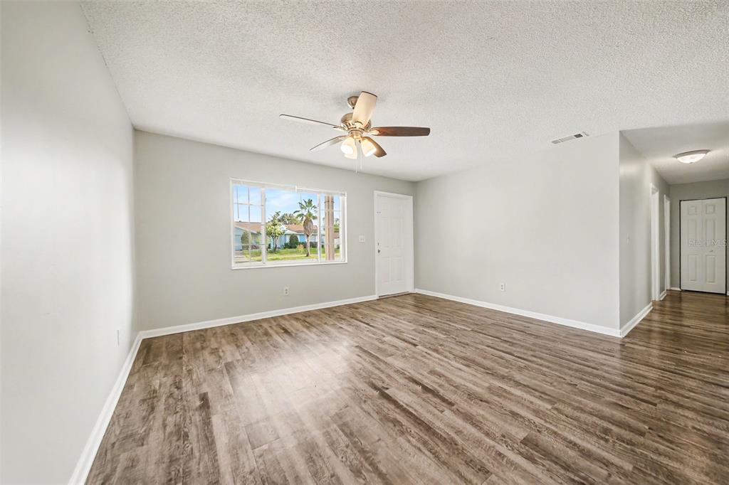 A galley kitchen features white cabinets, granite countertops, stainless steel appliances, and wood-look flooring — 4814 BLARNEY DRIVE, ORLANDO, FL