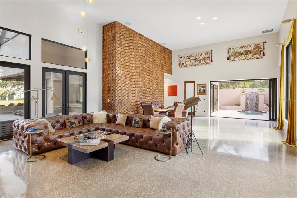 A spacious living room features a large leather sectional, polished concrete floors, and a textured wall — 49 OSPREY POINT DRIVE, OSPREY, FL