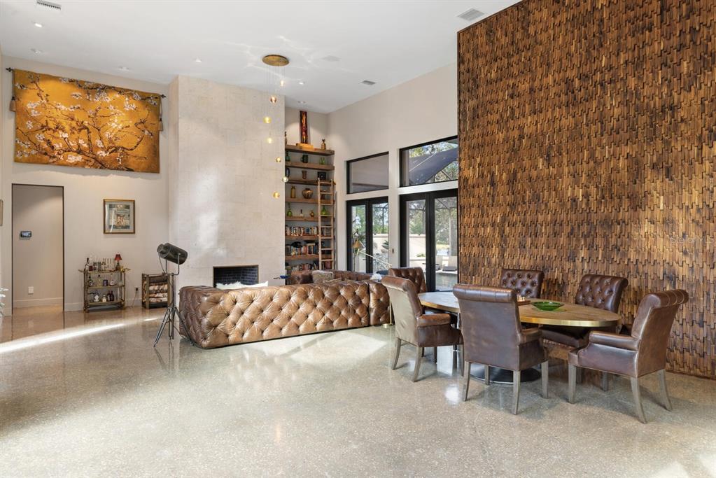 A spacious living and dining area features a textured wood wall, fireplace, and leather furniture — 49 OSPREY POINT DRIVE, OSPREY, FL