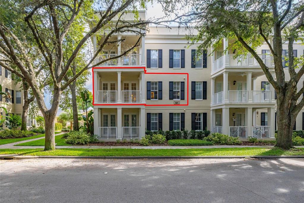 A three-story apartment building exterior features balconies, dark shutters, and a red-outlined unit — 921 BEGONIA ROAD UNIT 203, CELEBRATION, FL