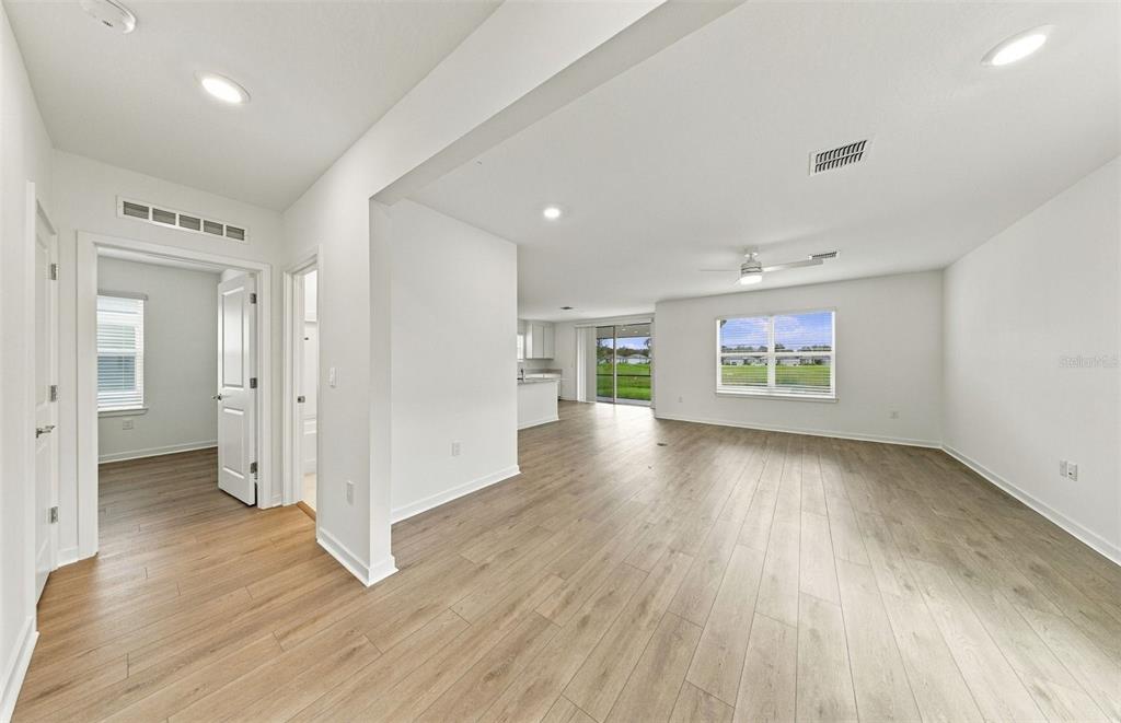 A modern kitchen features white cabinets, stainless steel appliances, quartz countertops, and light wood flooring — 9185 NEWMONS PLACE, WILDWOOD, FL