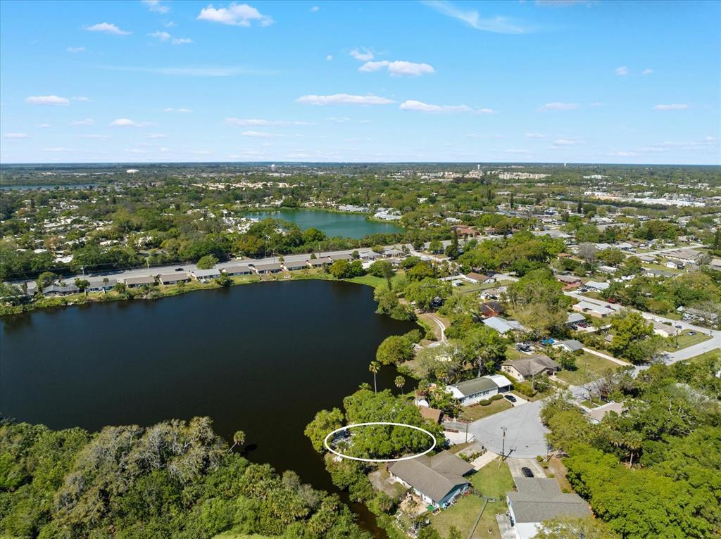 An aerial view shows a house with a white roof situated beside a dark lake — 5027 31ST STREET W, BRADENTON, FL