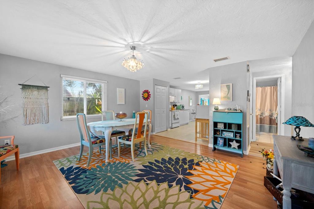 A dining room with a floral rug, wooden floors, and an open view into the kitchen — 5027 31ST STREET W, BRADENTON, FL