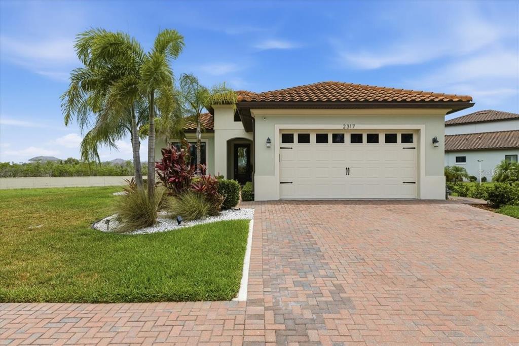 A brick walkway leads to the front entrance of a house with palm trees — 2317 5TH STREET E, PALMETTO, FL