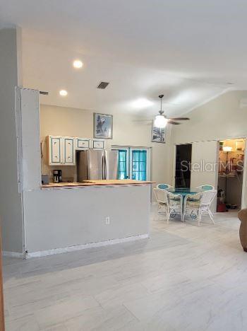 A kitchen with white cabinets and a breakfast bar opens into a dining area — 5411 THOMAS STREET, BOKEELIA, FL