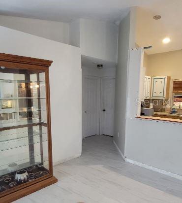 A view of a room with light-colored flooring, a wooden display cabinet, and a kitchen pass-through — 5411 THOMAS STREET, BOKEELIA, FL