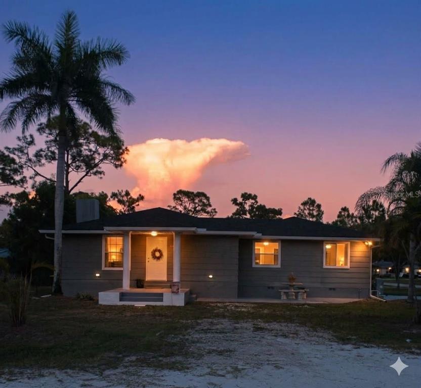 A single-story house with gray siding and a palm tree at sunset — 9082 ACORN BOULEVARD, PUNTA GORDA, FL