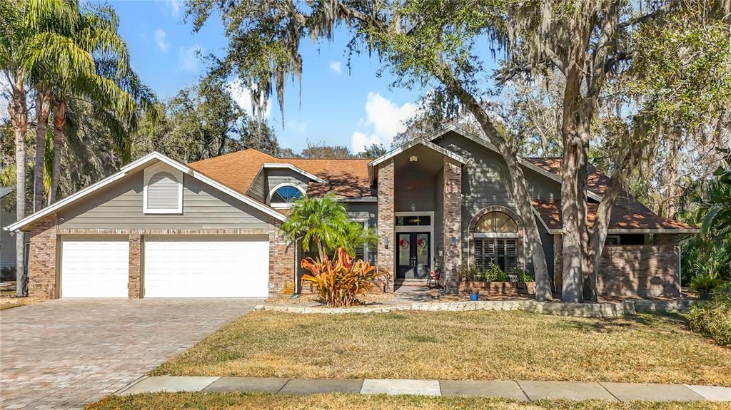 A single-story house with a brick and siding exterior, a two-car garage, and mature trees — 50 WILLOWOOD LANE, OLDSMAR, FL