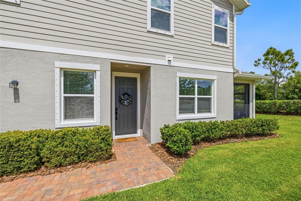The exterior of a two-story home features light siding, stucco, and a brick walkway — 6380 CAMINO DRIVE, APOLLO BEACH, FL
