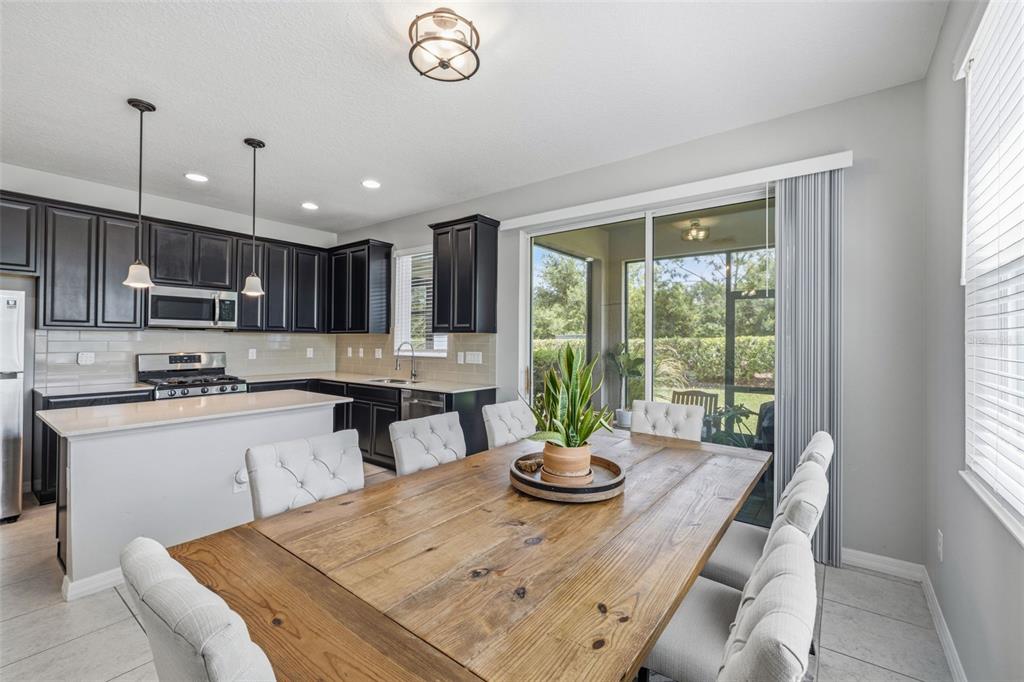A dining area with a wooden table and upholstered chairs sits beside a modern kitchen — 6380 CAMINO DRIVE, APOLLO BEACH, FL