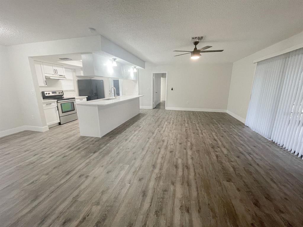A kitchen with white cabinets and a breakfast bar opens into a spacious living area — 12834 LAKE TREE LANE, HUDSON, FL