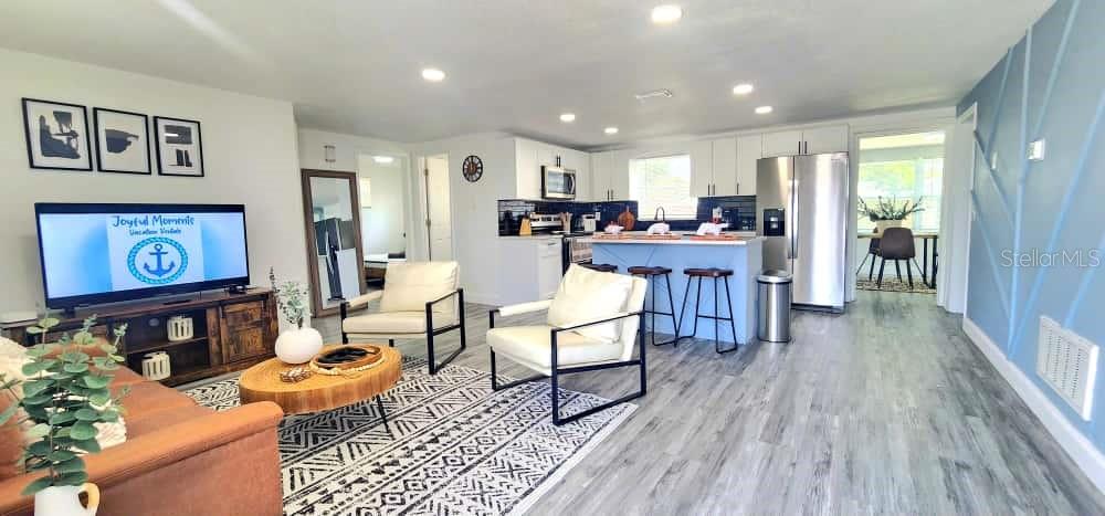 A kitchen features white cabinets, a stainless steel microwave, a black stove, and black backsplash — 4012 VALENCIA DRIVE, NEW PORT RICHEY, FL